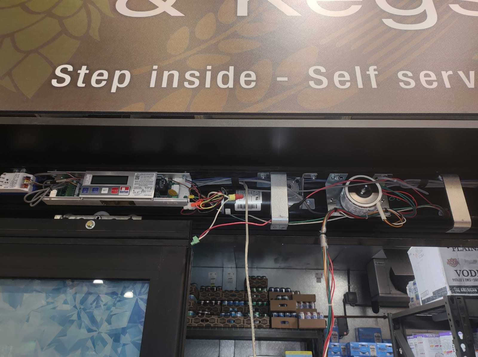 Exposed automatic door operator and control assembly above a storefront entrance