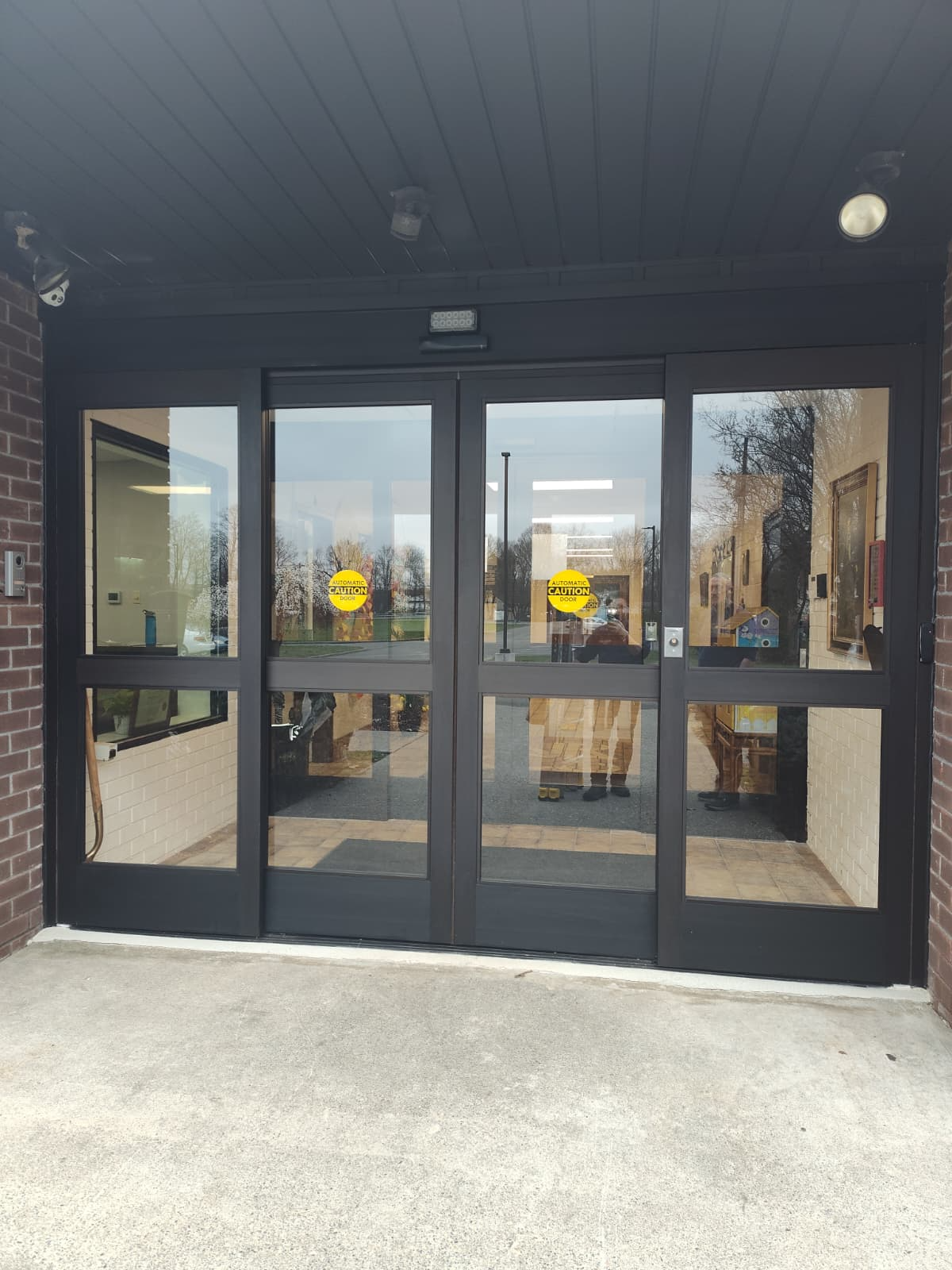 Black four-panel automatic glass entrance in a commercial lobby
